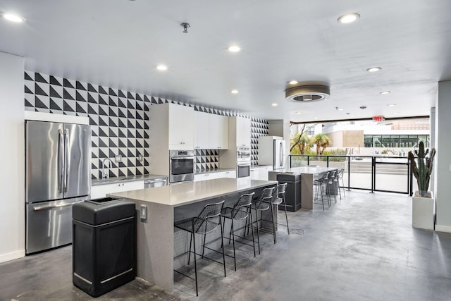 kitchen featuring appliances with stainless steel finishes, decorative backsplash, white cabinets, a breakfast bar, and a center island