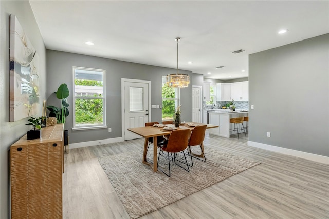 dining space featuring light wood-type flooring and a notable chandelier