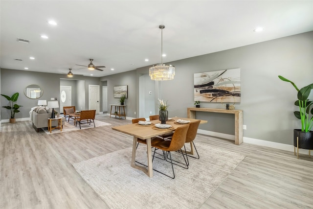 dining room featuring light hardwood / wood-style floors and ceiling fan with notable chandelier