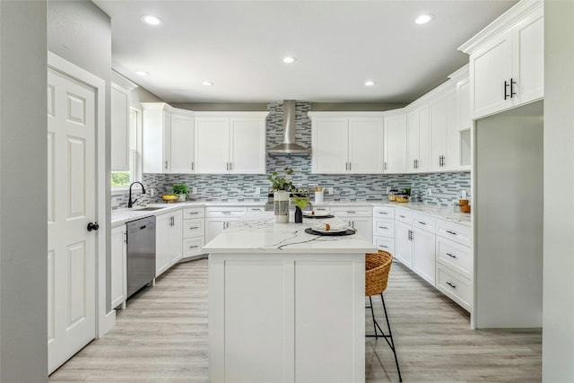 kitchen with dishwasher, a kitchen island, wall chimney exhaust hood, white cabinets, and a breakfast bar