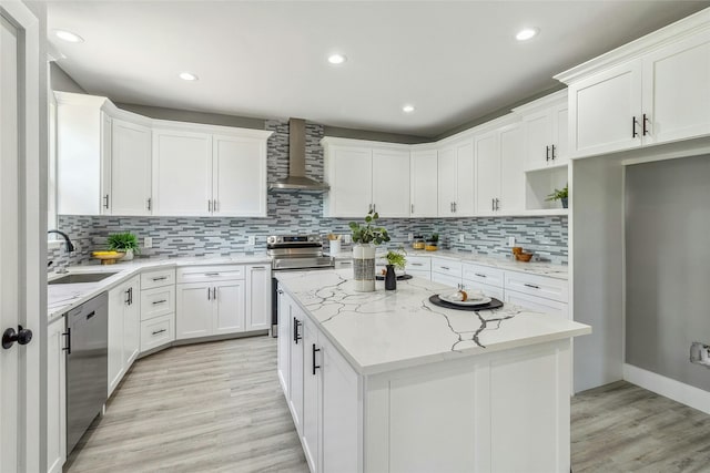 kitchen with a kitchen island, sink, stainless steel appliances, white cabinets, and wall chimney exhaust hood