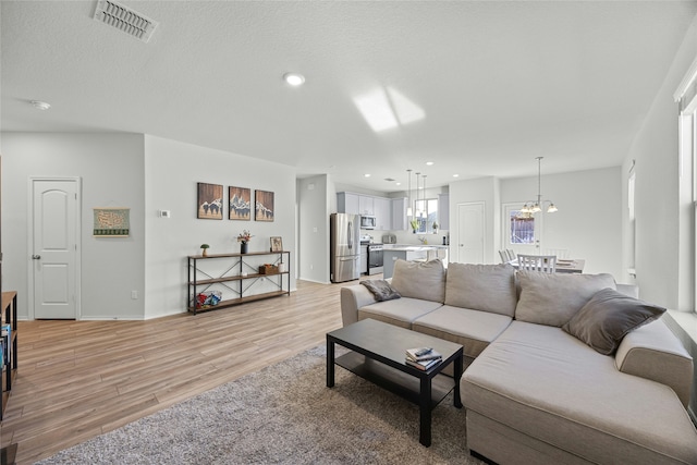 living room with a chandelier and light hardwood / wood-style flooring