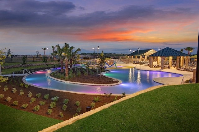 pool at dusk with a gazebo, a lawn, and a patio