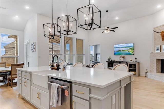 kitchen featuring hanging light fixtures, stainless steel dishwasher, a kitchen island, light hardwood / wood-style flooring, and ceiling fan