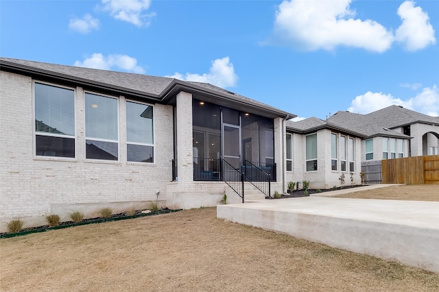 rear view of house featuring a sunroom, a yard, and a patio