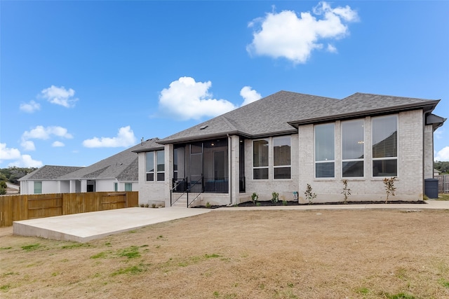 back of house with a sunroom, a patio area, and a lawn