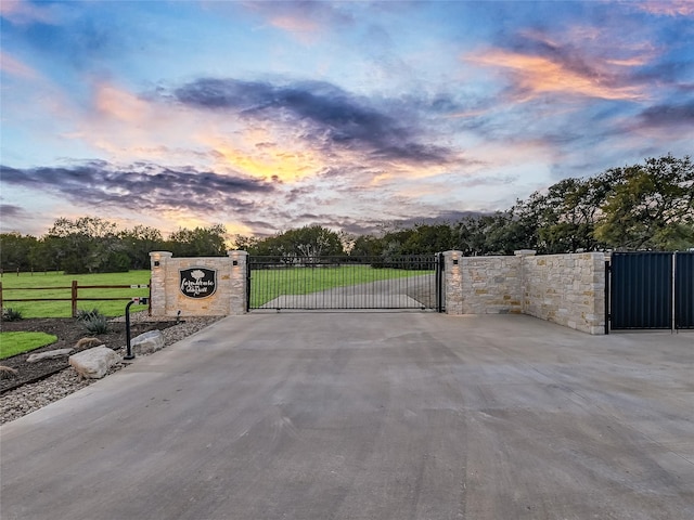 gate at dusk featuring a yard