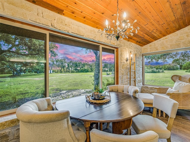 dining space with wood ceiling, hardwood / wood-style flooring, a healthy amount of sunlight, a notable chandelier, and vaulted ceiling