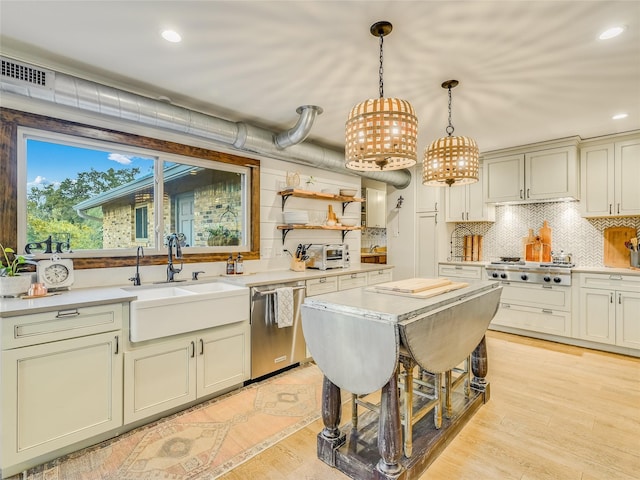 kitchen with appliances with stainless steel finishes, decorative backsplash, sink, hanging light fixtures, and light hardwood / wood-style floors