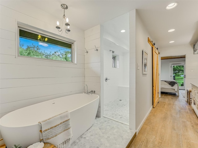 bathroom featuring a notable chandelier, plus walk in shower, and hardwood / wood-style floors