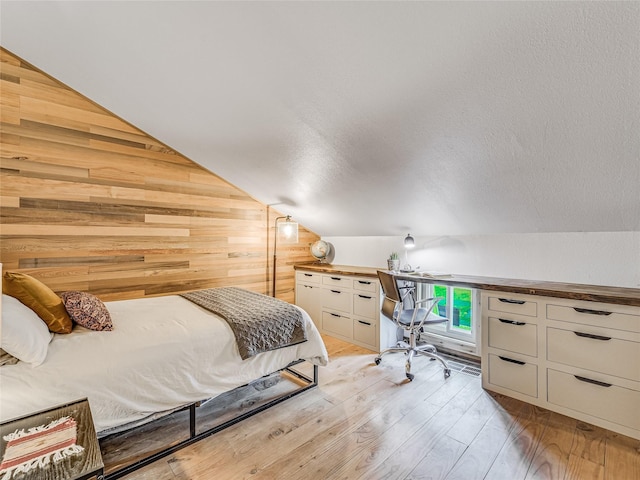 bedroom with lofted ceiling, light wood-type flooring, and wooden walls