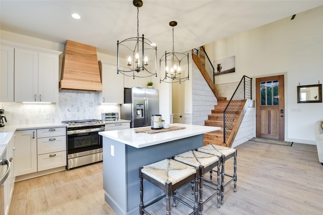 kitchen featuring white cabinets, stainless steel appliances, wall chimney exhaust hood, and a kitchen island