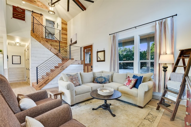 living room with ceiling fan, high vaulted ceiling, light hardwood / wood-style flooring, beam ceiling, and a barn door