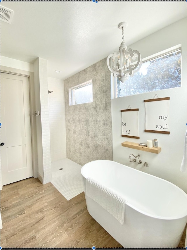 bathroom featuring independent shower and bath, hardwood / wood-style flooring, and an inviting chandelier