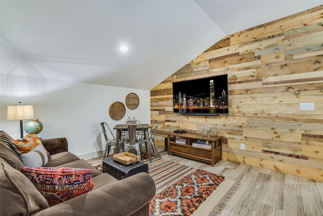 living room with vaulted ceiling, light hardwood / wood-style flooring, and wooden walls