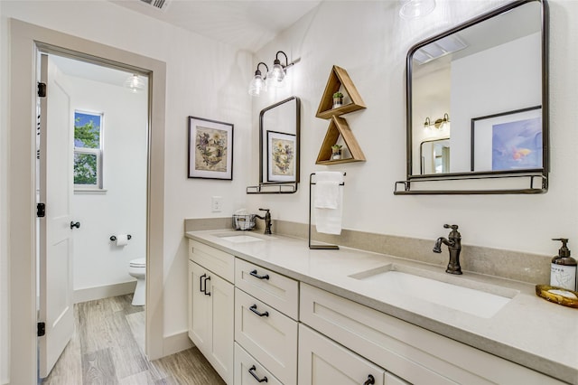 bathroom with toilet, vanity, and hardwood / wood-style floors