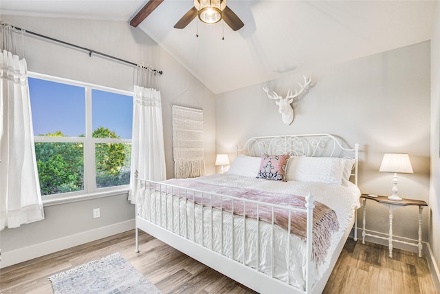 bedroom with ceiling fan, vaulted ceiling with beams, and hardwood / wood-style floors