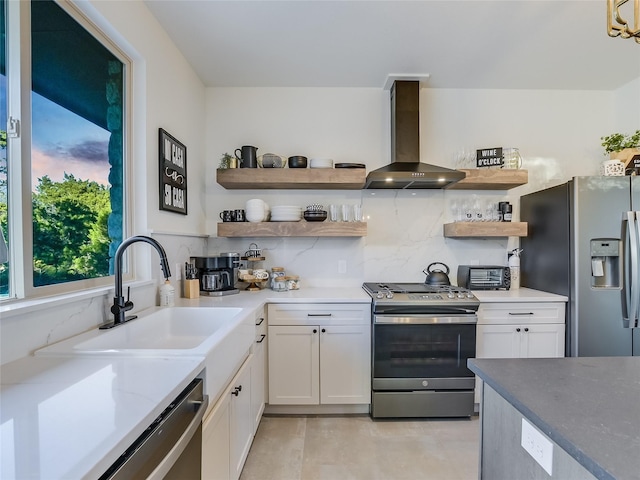 kitchen with wall chimney exhaust hood, white cabinets, sink, and stainless steel appliances