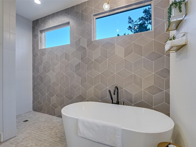 bathroom with a healthy amount of sunlight, plus walk in shower, and tile walls