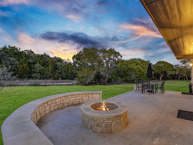 patio terrace at dusk with an outdoor fire pit and a yard