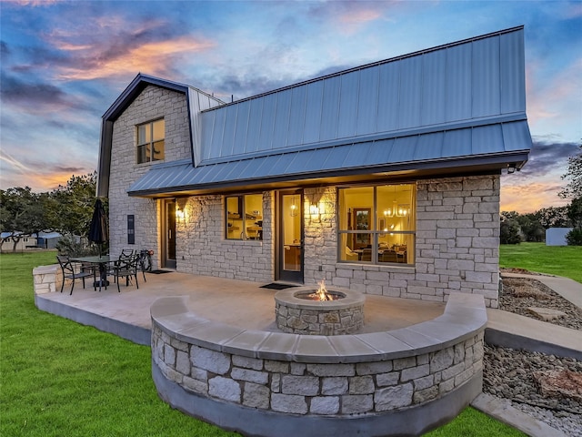 back house at dusk with an outdoor fire pit, a yard, and a patio