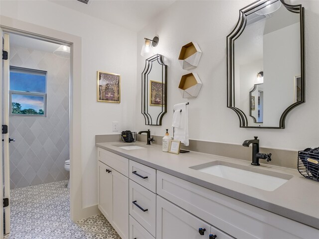 bathroom with toilet, vanity, and tiled shower