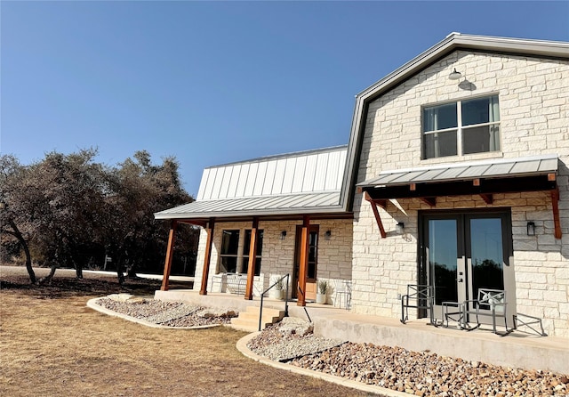 rear view of property with covered porch and french doors