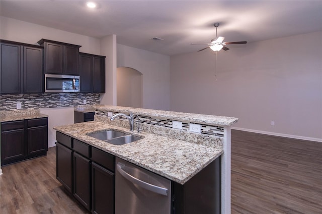 kitchen featuring sink, backsplash, appliances with stainless steel finishes, and a center island with sink