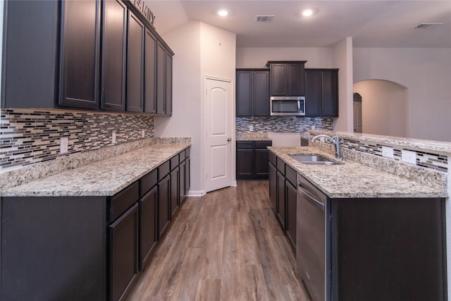 kitchen featuring backsplash, appliances with stainless steel finishes, sink, and hardwood / wood-style flooring