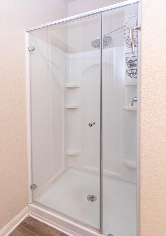 bathroom with wood-type flooring and an enclosed shower