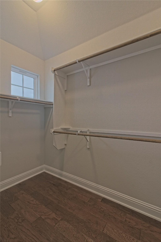 walk in closet with dark wood-type flooring and lofted ceiling