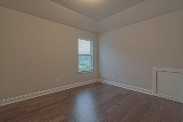 spare room with dark hardwood / wood-style flooring and lofted ceiling