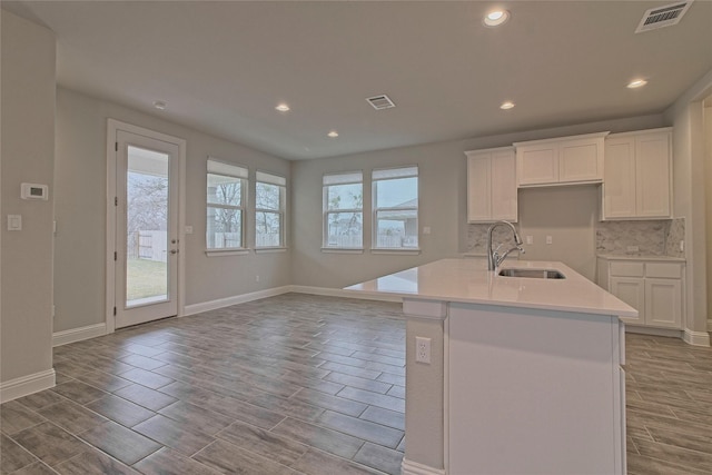 kitchen with white cabinetry, decorative backsplash, a center island, and sink