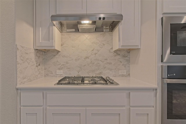 kitchen featuring white cabinets, appliances with stainless steel finishes, tasteful backsplash, and range hood