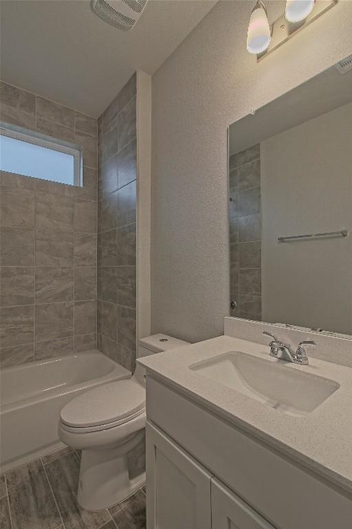 full bathroom with toilet, vanity, and tiled shower / bath combo