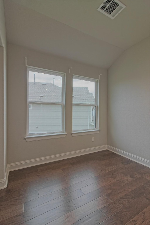 spare room with plenty of natural light, dark hardwood / wood-style floors, and vaulted ceiling