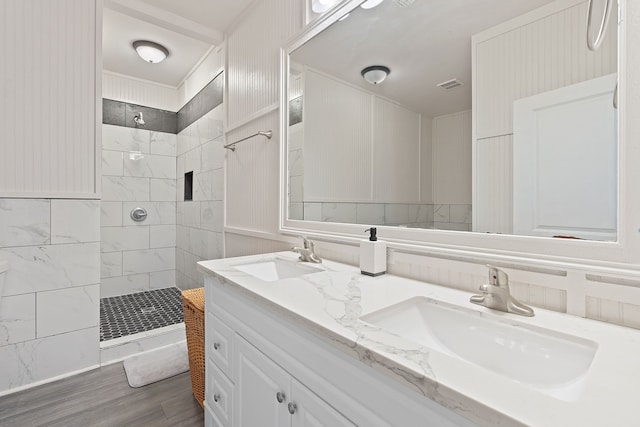 bathroom with wood-type flooring, vanity, and a tile shower