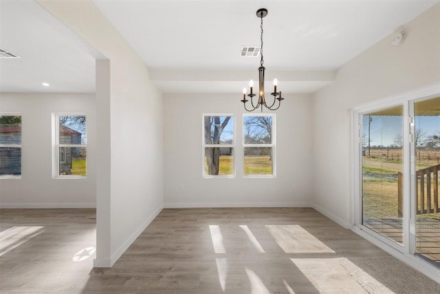 unfurnished dining area with an inviting chandelier and light hardwood / wood-style flooring