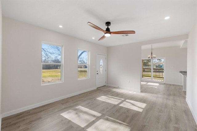 interior space featuring ceiling fan with notable chandelier and light hardwood / wood-style flooring