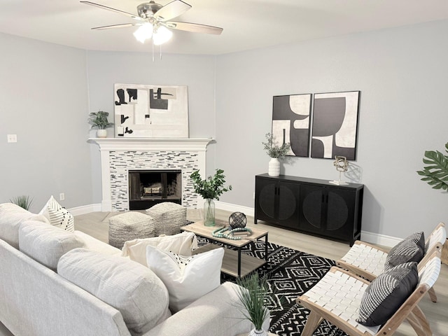 living room featuring ceiling fan, a fireplace, and light hardwood / wood-style flooring