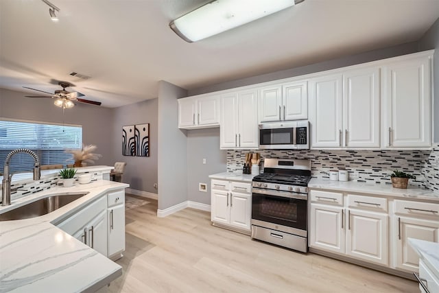 kitchen featuring appliances with stainless steel finishes, white cabinets, tasteful backsplash, and sink