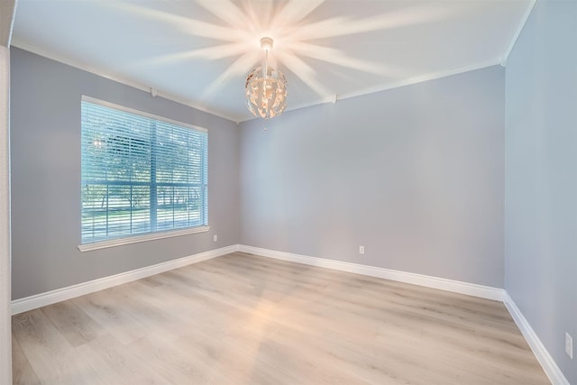 empty room featuring an inviting chandelier, crown molding, and light hardwood / wood-style flooring