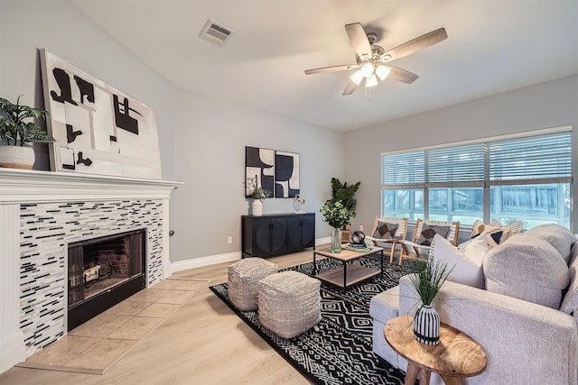 living room featuring light wood-type flooring, ceiling fan, and a fireplace