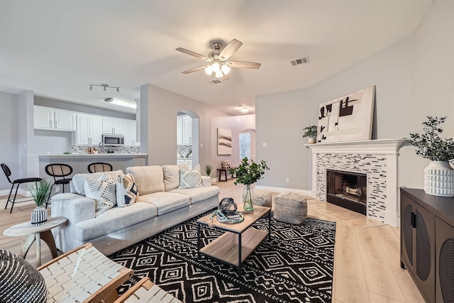 living room featuring light hardwood / wood-style floors, ceiling fan, and a fireplace