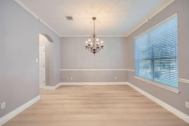 empty room with crown molding, light hardwood / wood-style flooring, and a notable chandelier