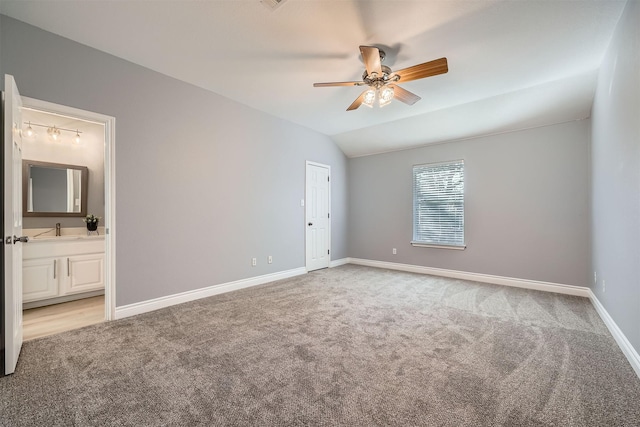 carpeted empty room featuring ceiling fan, vaulted ceiling, and sink