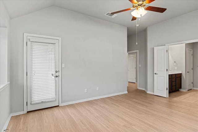 interior space with ceiling fan, vaulted ceiling, connected bathroom, and light hardwood / wood-style floors