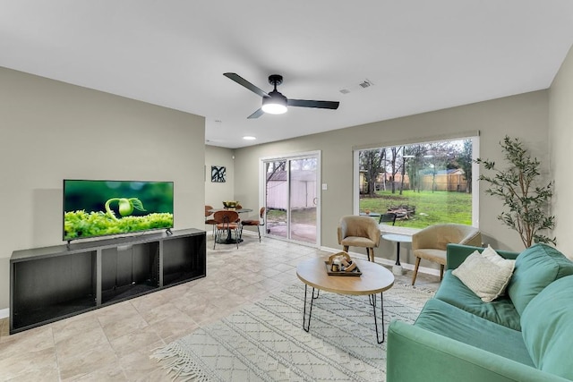 living room with baseboards, visible vents, and ceiling fan