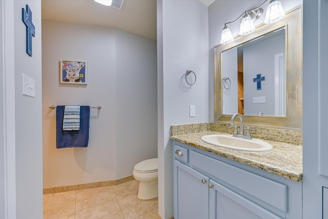 bathroom with toilet, vanity, and tile patterned floors