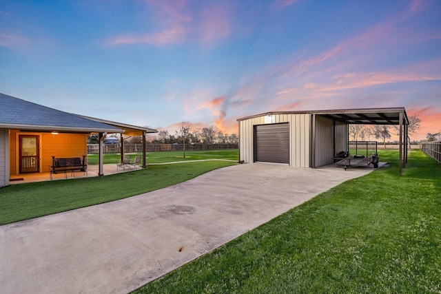 garage at dusk featuring a yard